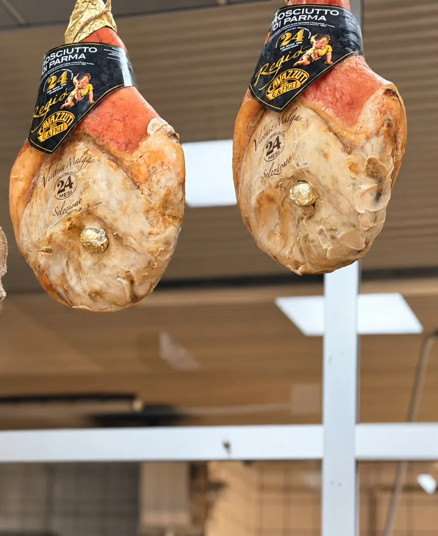 I prosciutti di Parma appesi sopra il banco